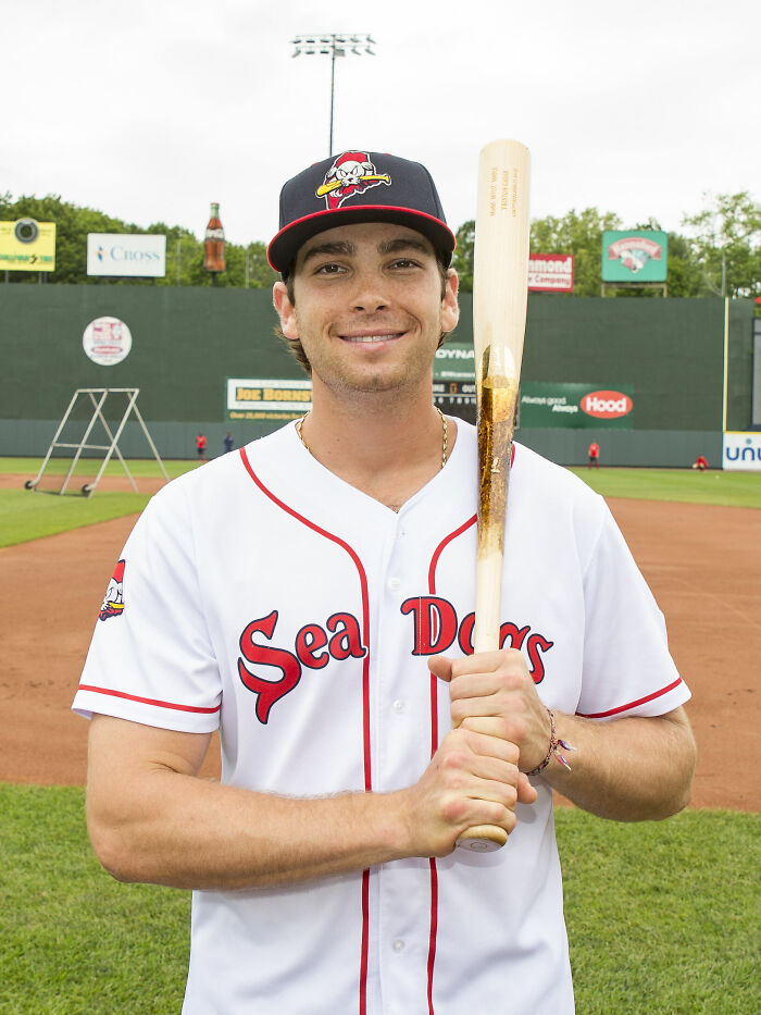Triston Casas in a Sea Dogs baseball uniform holding a bat on a baseball field during daytime.