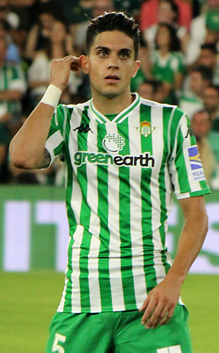 Marc Bartra in green and white striped football jersey playing on the field during a match.