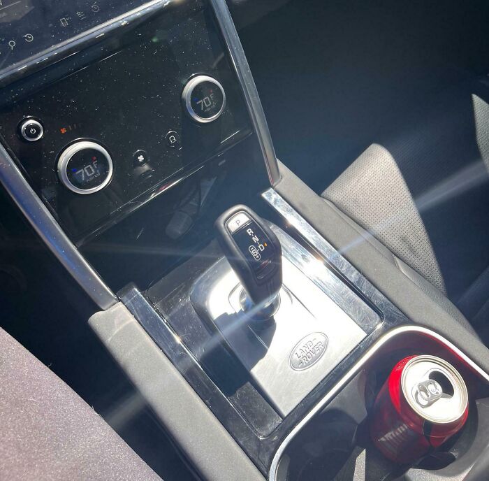 Car gear shift and temperature controls with a poorly placed cup holder in a terrible product design example.