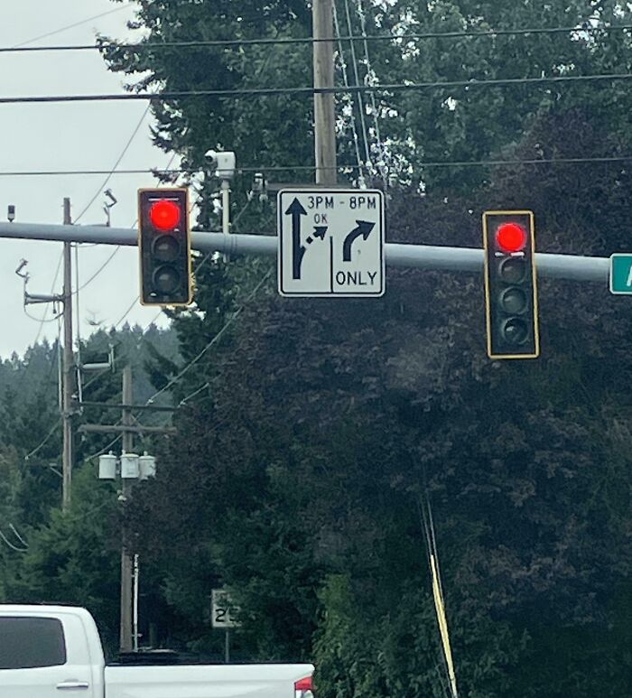Traffic lights with confusing directional sign showing contradictory left and right turn arrows, a terrible product design example.