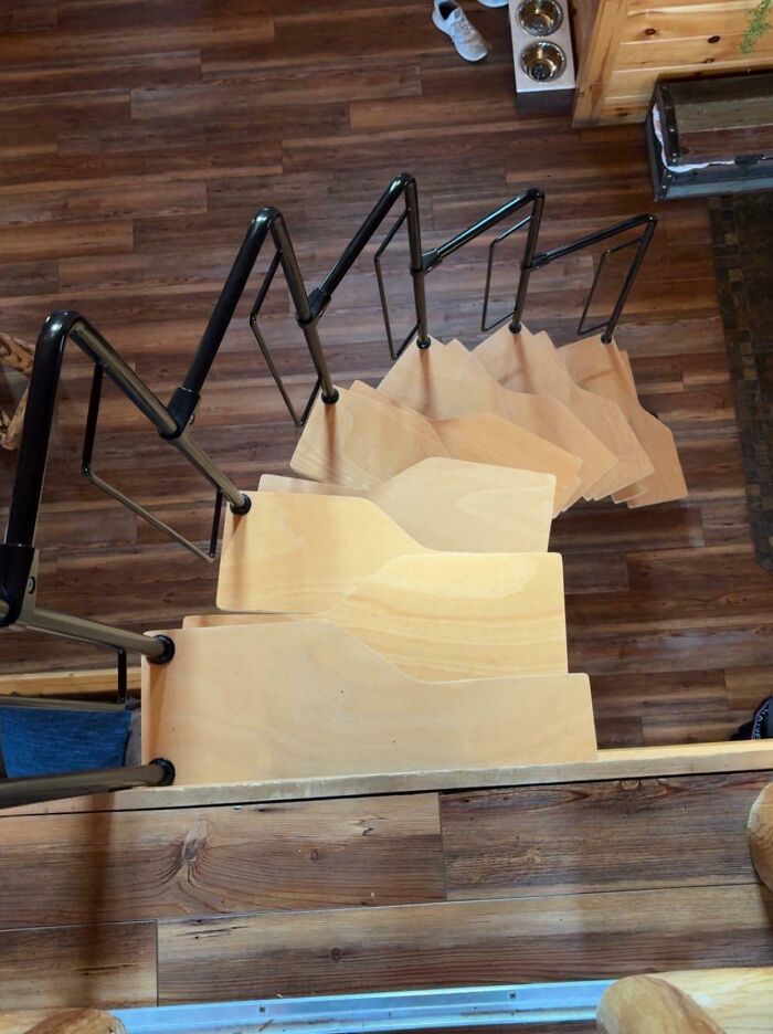 Unusual product design of wooden stairs with uneven steps and oddly placed handrails causing safety concerns.