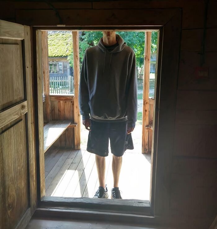 Tall person standing in a low doorway, illustrating common struggles only tall people face in daily life.