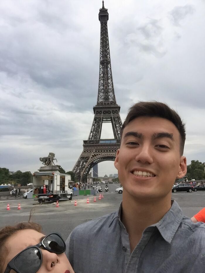 Two people, one noticeably tall, taking a selfie near the Eiffel Tower, illustrating struggles only tall people face outdoors.