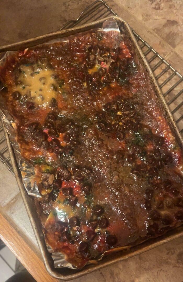 Burnt and melted dessert with chocolate chips on a baking tray, showing a ruined dessert fail.