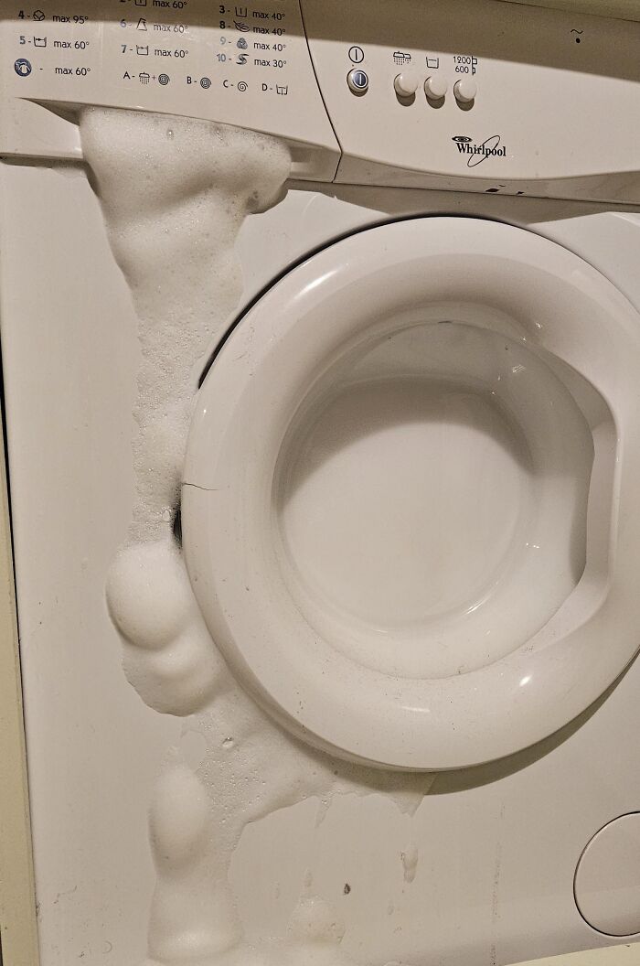 Foaming washing machine fail with soap bubbles overflowing, showing an expensive and unfortunate home appliance mistake.