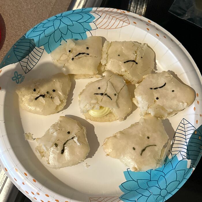 Broken and c*****d cookies with sad faces drawn, showing creative ways people managed to ruin dessert unexpectedly.