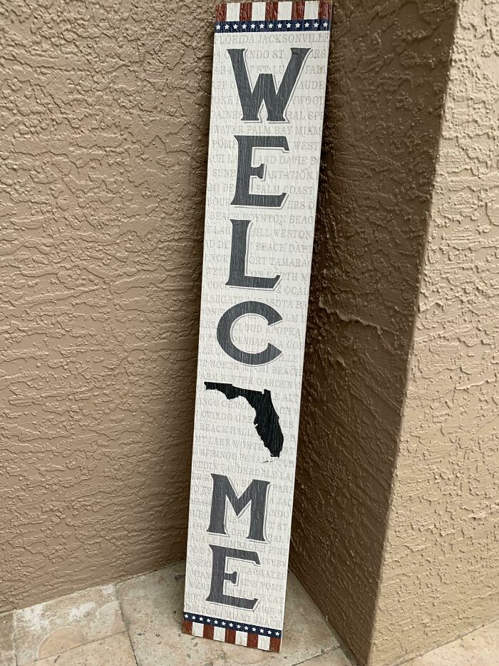 Wooden sign spelling welcome with the letter L replaced by a Florida state silhouette, a design fail by designers.