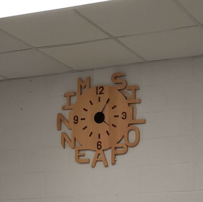 Wall clock with jumbled letters instead of numbers, showing a design fail by designers attempting to write something.