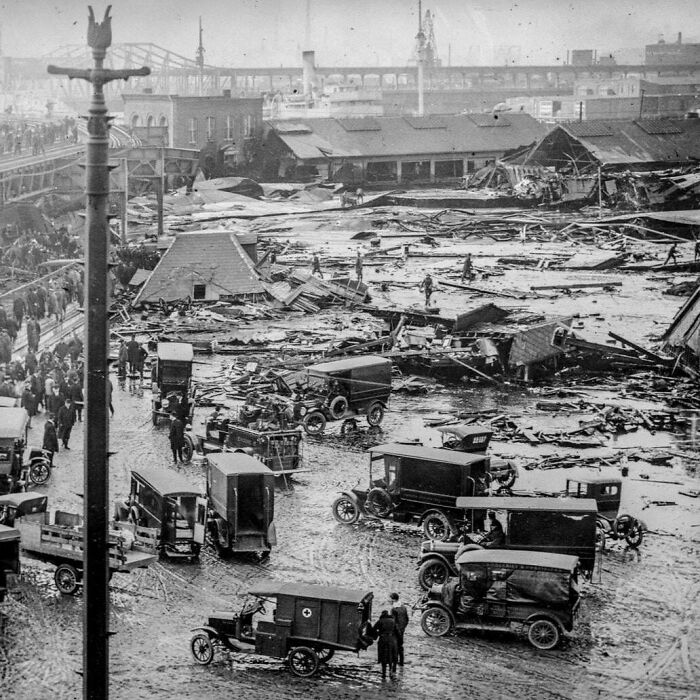 Black and white US history photo showing 1920s vehicles and rescue efforts amid disaster rubble and destruction.