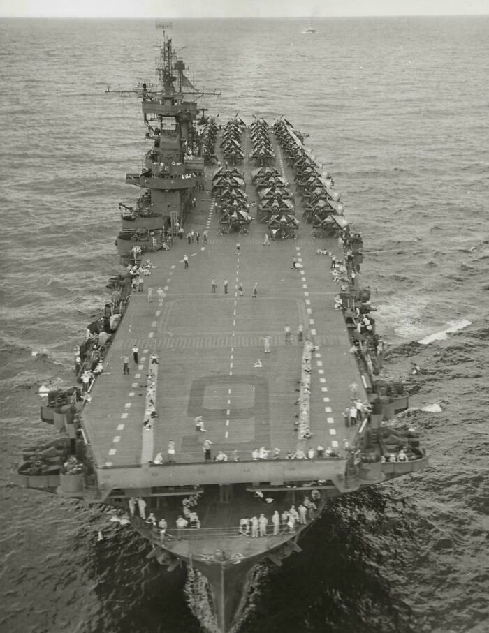 Vintage US aircraft carrier at sea with planes on deck and crew members, a unique US history photo showing the past.
