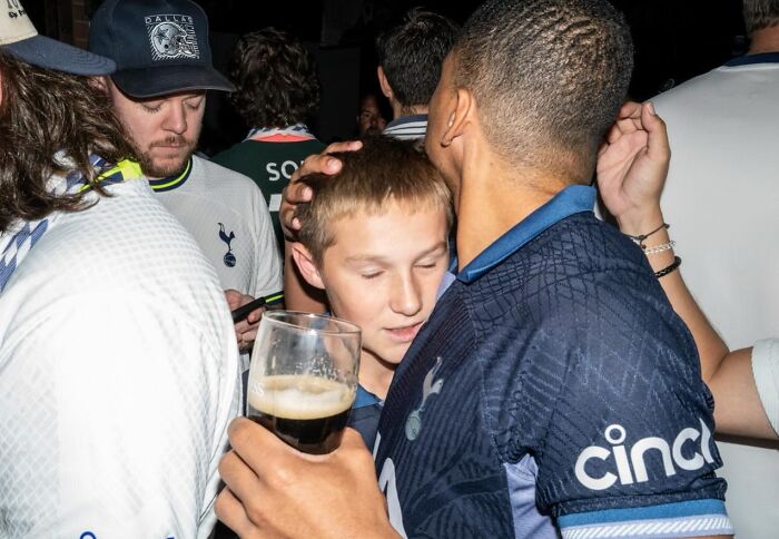 Young fans share a close moment at a crowded event, captured in candid street photos by Perry Hall.