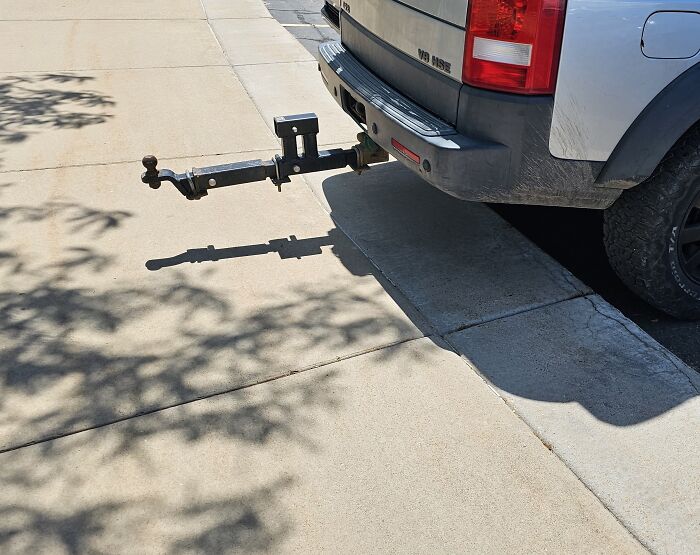Pickup truck parked with trailer hitch extending over the sidewalk, showing an example of dumb drivers causing hazards.