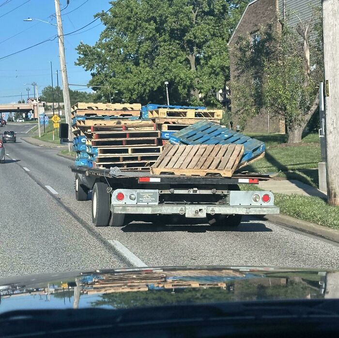 Truck carrying unsecured wooden pallets on the road, illustrating dumb drivers being shamed for unsafe driving.