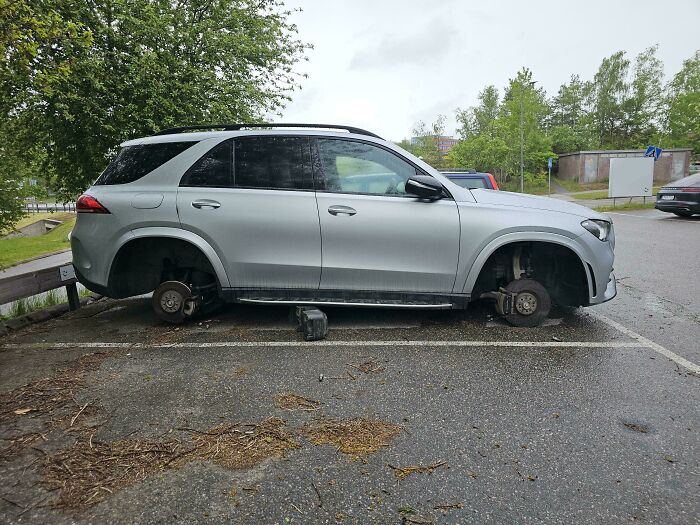 Silver SUV parked without wheels in a lot, illustrating unfortunate events that can make you feel better about your own day.