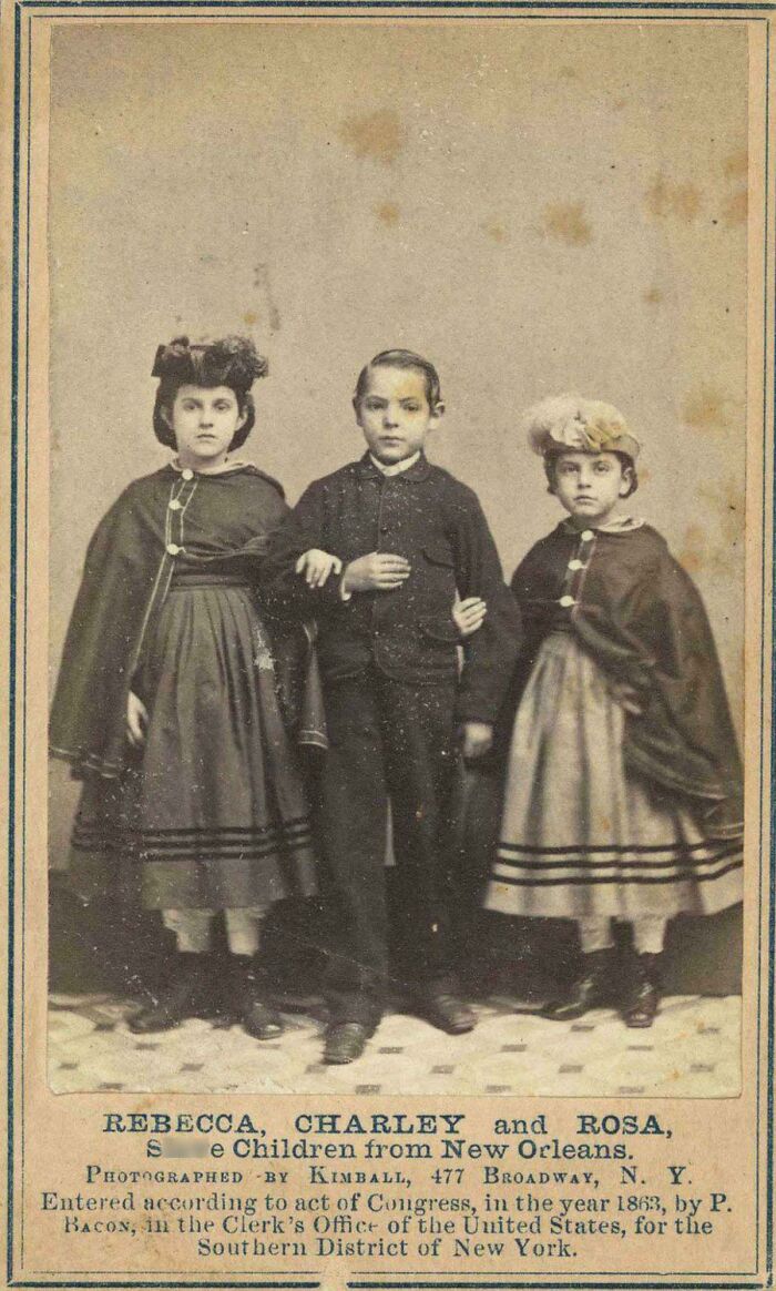 Three children from New Orleans in historical clothing posing for a vintage photograph depicting a world you'd hardly recognize today.
