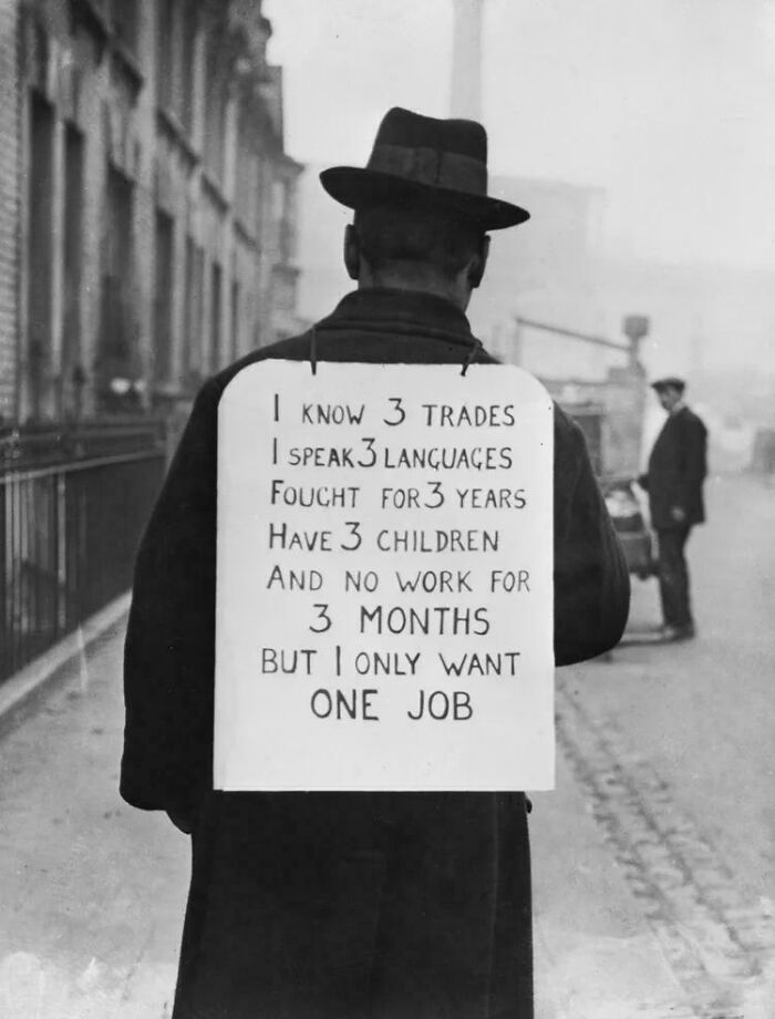 Man wearing a sign detailing his skills and struggles, representing interesting historical photographs of a world hardly recognized today.