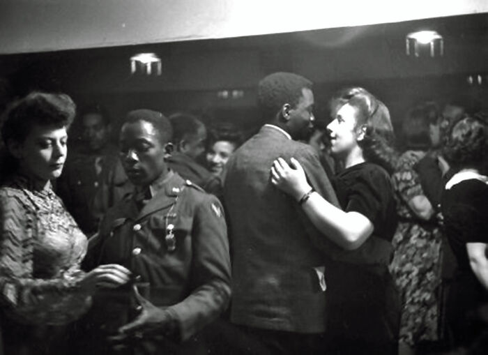 Black and white historical photograph showing couples dancing closely in a crowded room, depicting a world you'd hardly recognize today.