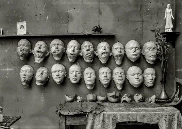 Collection of historical death masks displayed on a wall, showcasing faces from a world you'd hardly recognize today.