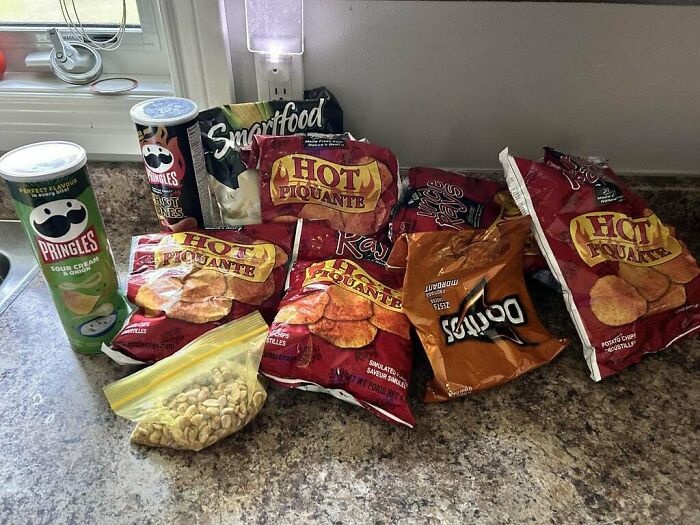 Multiple bags of chips and snacks arranged on a kitchen counter showing an example of men being men behavior.