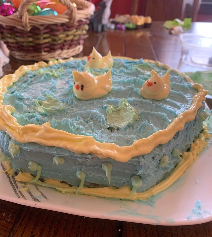 Blue frosted cake with uneven icing and misshaped ducks, an example of people managing to ruin dessert unexpectedly.
