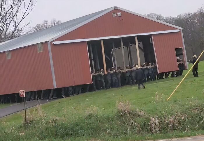 Group of people lifting a large barn in a field demonstrating an unusual but effective solution example.