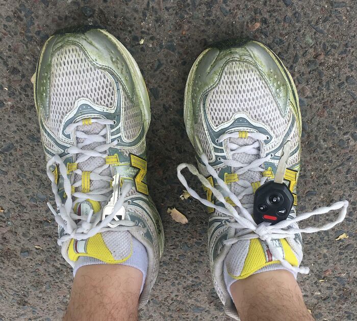 Worn running shoes with tied laces holding a car key, illustrating if it's stupid but it works then it's not stupid idea.
