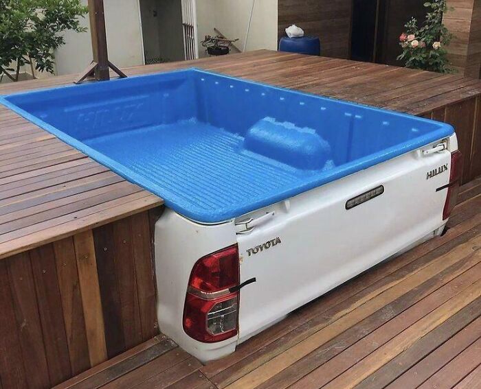 Pickup truck bed repurposed as a blue plastic pool embedded in wooden decking, showcasing creative if it’s stupid but it works.