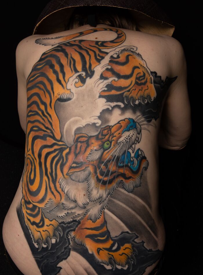 Large detailed tiger tattoo covering the entire back with vivid orange and black ink, showcasing cool tattoo art design.