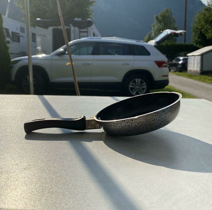 Small frying pan with a broken handle resting on a table outdoors, showing a terrible product design flaw.