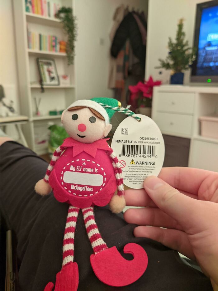Plush female elf toy with a name tag, highlighting examples of gendered nonsense in holiday decorations.