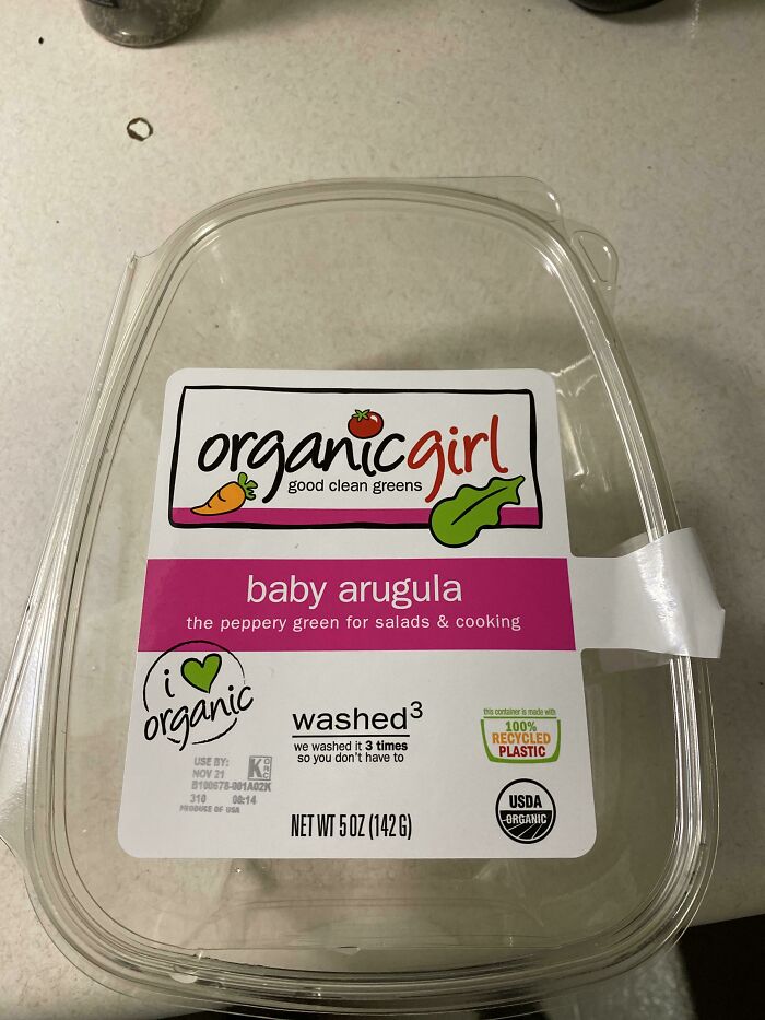 Plastic container of organic baby arugula greens with a pink label, highlighting organic and recycled plastic packaging.