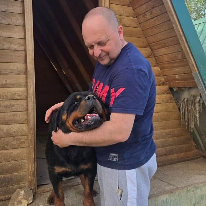 Man in a navy shirt caring for a large Rottweiler dog at Serbia&rsquo;s largest abandoned and rescued animal shelter.