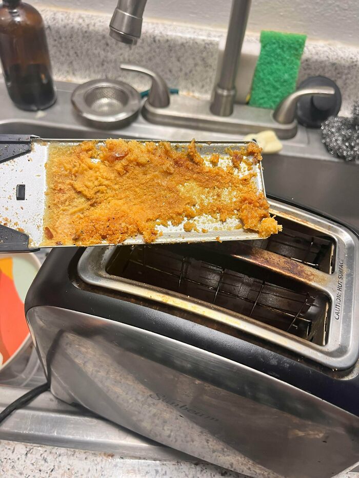 Dirty toaster crumb tray covered in old food residue, showing a jerk roommate's neglect of cleaning duties.
