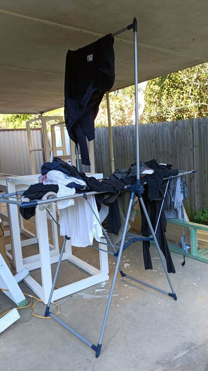 Clothes haphazardly draped over a drying rack under a patio, showcasing jerks that made roommates consider living alone.
