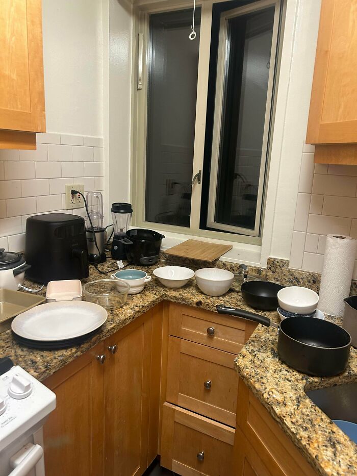 Cluttered kitchen countertop with unwashed dishes and appliances, showing jerks that made roommates consider living alone.