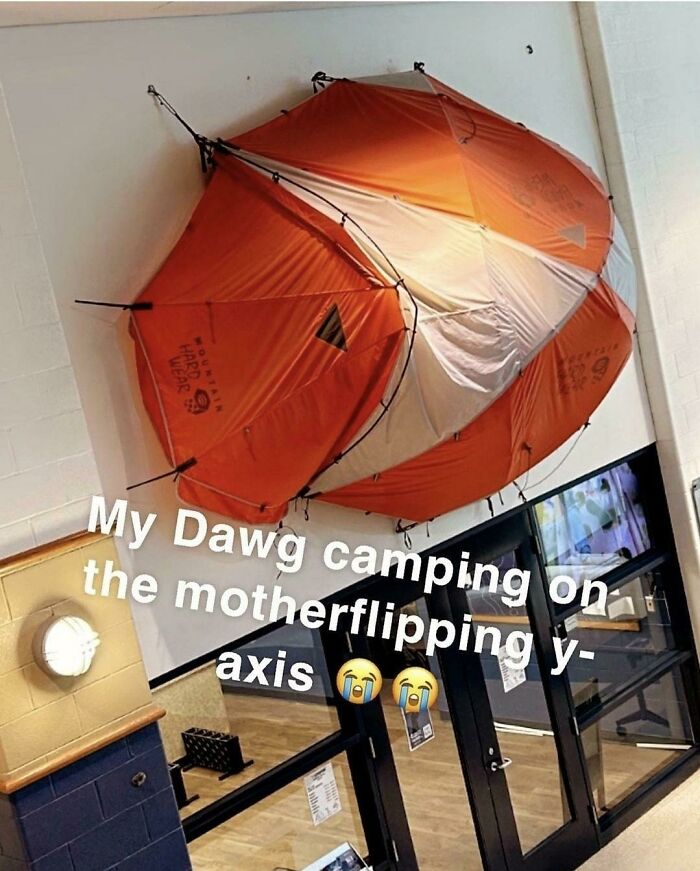 Bright orange tent mounted upside down on a wall inside a building, a funny screenshot people took with humorous text.