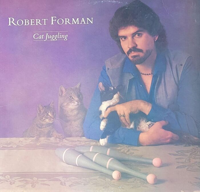 Album cover featuring a man holding a cat with juggling pins on the table, illustrating hilariously bad album covers sold.