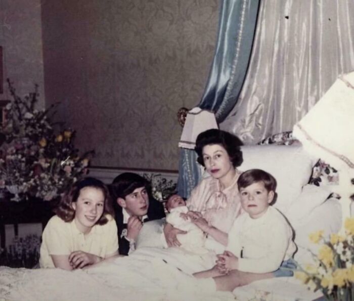 Historical photograph showing a family with mother and children in a vintage bedroom setting from a past world.