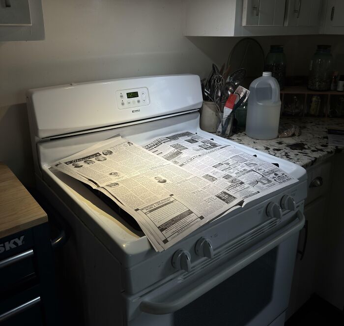 Newspaper left on a stove in a messy kitchen showing jerks that made roommates consider living alone.