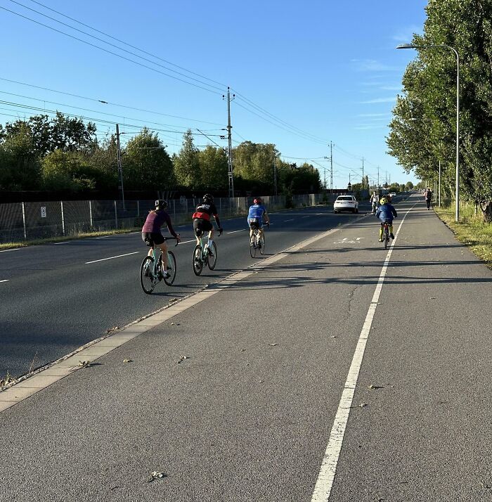 Group of cyclists riding closely on a road with cars nearby, highlighting issues related to dumb drivers and road safety awareness.