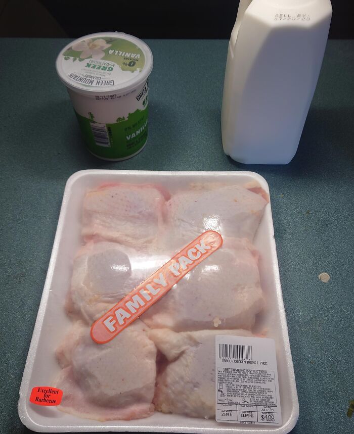 Pack of raw chicken thighs labeled family pack on a counter next to a yogurt cup and a milk carton showing messy roommate behavior.
