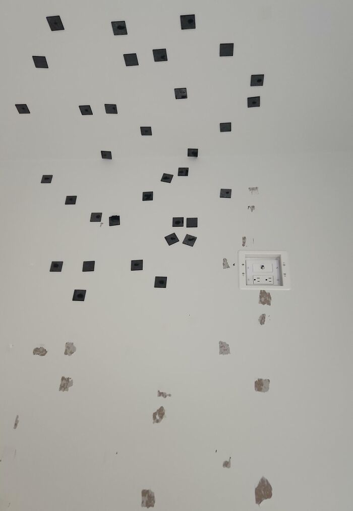 Black tape squares randomly placed on white ceiling and walls showing destructive behavior by jerks in roommate situations.