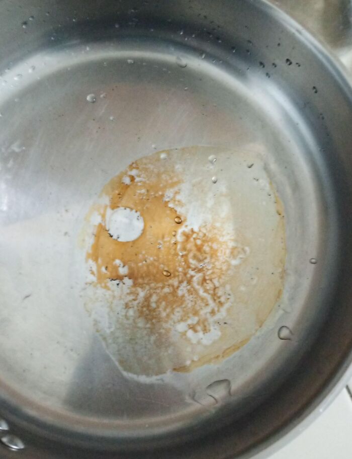 Stainless steel pot with a burnt and stained bottom, showing neglect that could frustrate roommates sharing a kitchen.