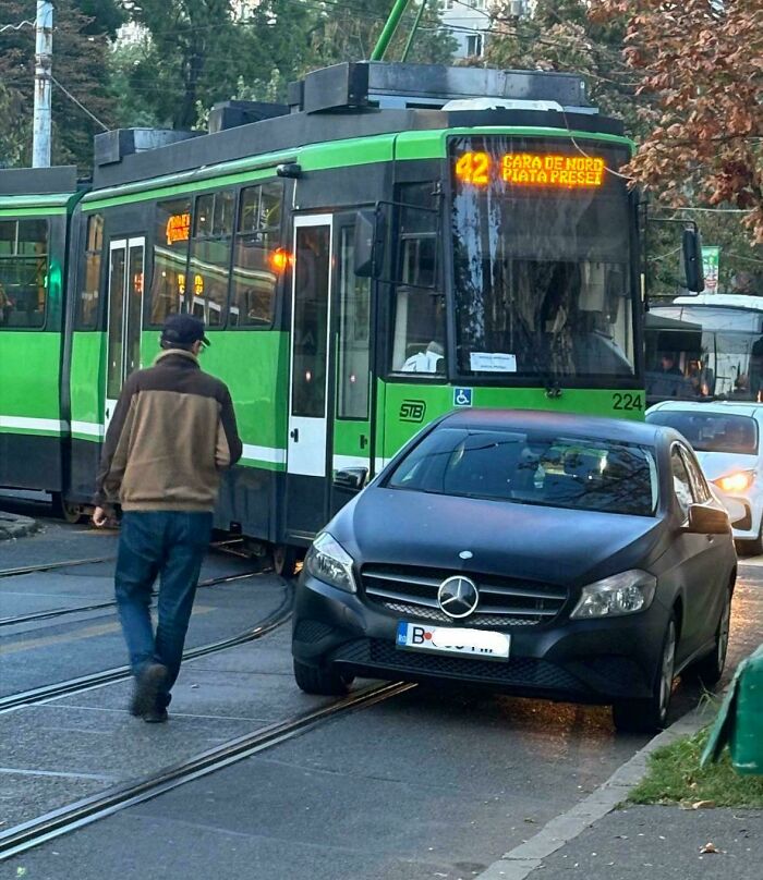 Black Mercedes parked on tram tracks blocking public transport, illustrating dumb drivers causing traffic disruptions in urban area.