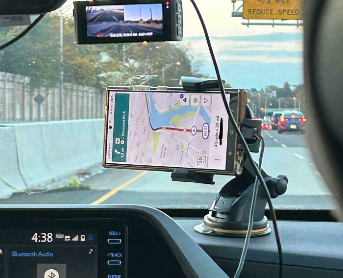 Dashboard view showing GPS navigation and traffic on a highway, highlighting distracted driving among dumb drivers.