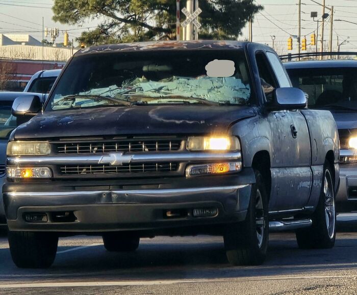 Black Chevrolet pickup with c*****d windshield and damaged body, illustrating dumb drivers shamed in viral photos.