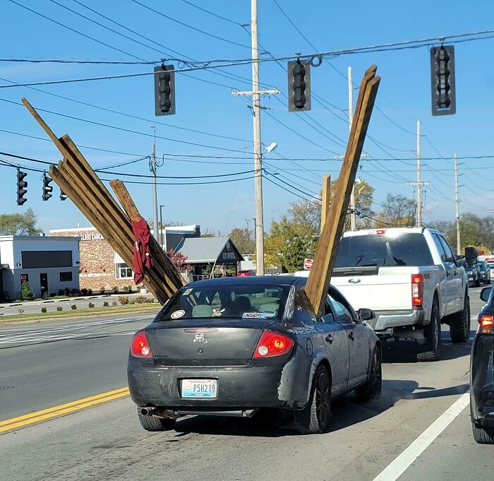 Car with large wooden planks protruding dangerously while driving, showing careless behavior of dumb drivers on the road.