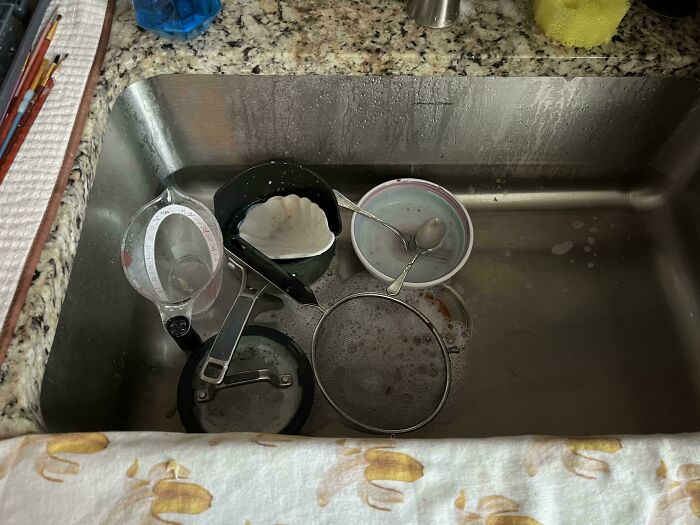 Kitchen sink filled with dirty dishes, showing infuriating examples of men being men in everyday chores.