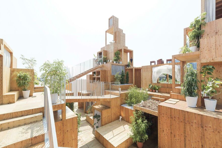Modern Japanese architecture featuring multi-level wooden structures with plants in a bright open space design.