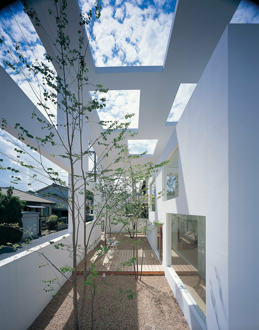 Modern Japanese architecture featuring open ceiling design, natural light, and minimalist outdoor courtyard with trees and wood decking.
